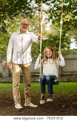family, happiness, generation, home and people concept - happy grandfather and  granddaughter swinging on teeterboard outdoors