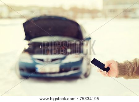 transportation, winter and vehicle concept - closeup of man with broken car and smartphone