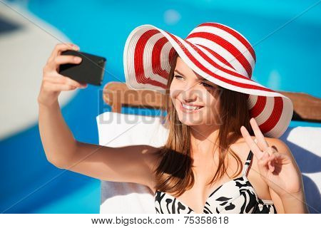 Smiling young woman with telephone on chaise longue