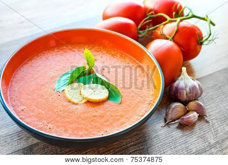 A bowl of tomato soup gaspacho with basil and crackers