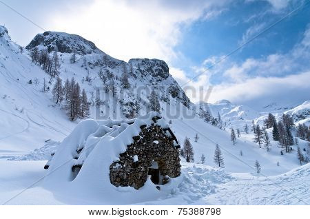 Mountain hut made of stones at winter in Slovenian Alps