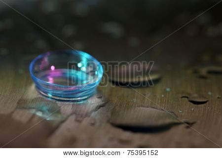 Contact lens with water drops on bright background