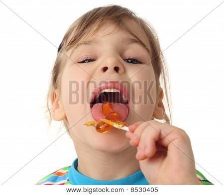 Niña lamiendo Lollipop naranja y mirando a cámara, aislado en blanco