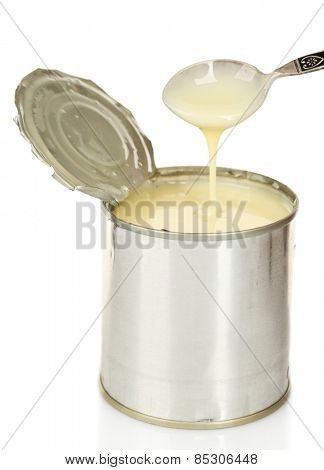 Tin can of condensed milk with spoon isolated on white