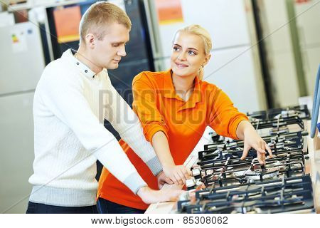Young man choosing kitchen range cooker in home appliance shopping mall supermarket