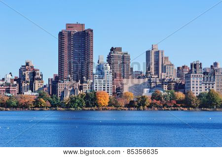 Central Park Autumn with New York City Manhattan Midtown skyline skyscrapers over lake with colorful foliage and clear blue sky.