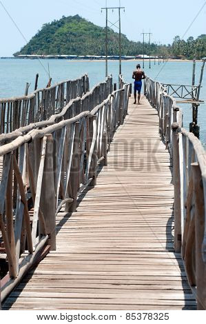 Man walking at traditional Wooden  Long Bridge Over The Sea,Thailand.