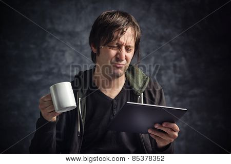 Man Reading Bad News On Digital Tablet Computer