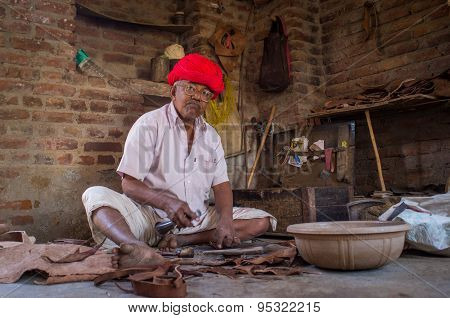 GODWAR REGION, INDIA - 13 FEBRUARY 2015: Elderly Indian shoemaker from Rabari tribe makes new pair of traditional shoes in workshop. Rabari or Rewari are an Indian community in the state of Gujarat.