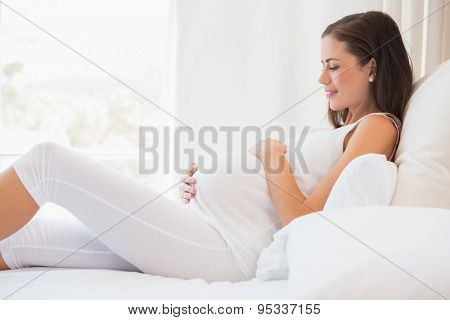 Happy pregnancy sitting on sofa at home in bedroom