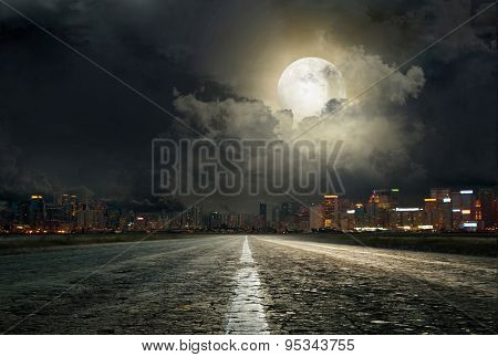 asphalt road leading into the city at night