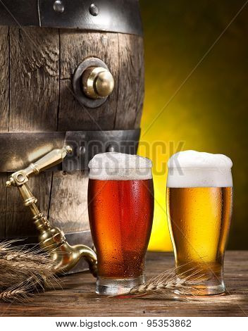 Still life: old wooden pin of beer, glass of beer and wheat on the table in the cellar.