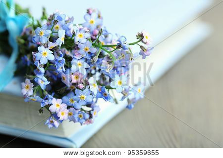 Forget-me-nots flowers on book, on wooden background