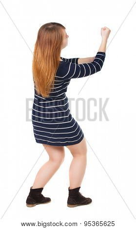 back view of standing woman pulling a rope from the top or cling to something.  Rear view people collection.    Isolated over white background. girl in dark blue dress pulling a rope from the top.