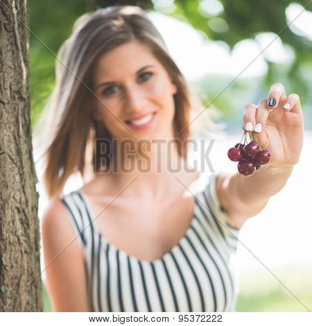 Young woman hlding fresh, ripe sour cherry