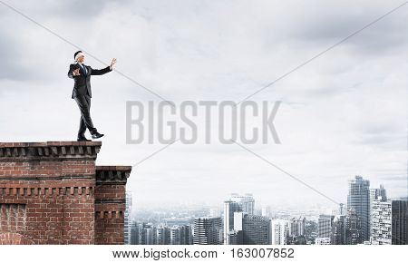 Businessman with blindfolder on eyes walking on building top