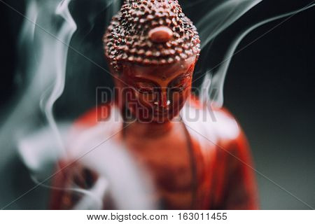 Buddha statue with incense. Deity and symbols of Buddhism. The practice of Buddhism and its symbols. Spiritual life of Asia
