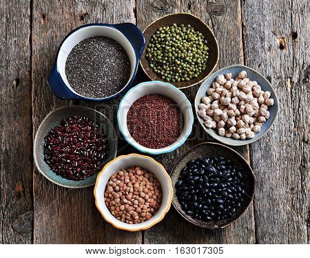 Healthy food - lentils, chickpeas, black beans, red beans, peas, quinoa and chia seeds on old wooden background.