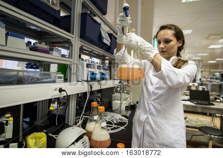 Woman Laboratory Assistant With Flask In His Hand In The Biochemical Laboratory