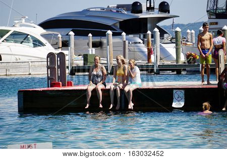 HARBOR SPRINGS, MICHIGAN / UNITED STATES - AUGUST 3, 2016: Swimmers sit on the edge of a raft at the Zorn Park Public Beach near downtown Harbor Springs.