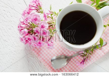 Morning coffee or cup of tea with pink flowers on wooden white rustic table. Selective Focus.