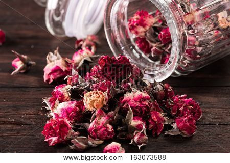 Rose Petals And Dried Flowers In Jar On Old Wooden Table. Healthy Concept