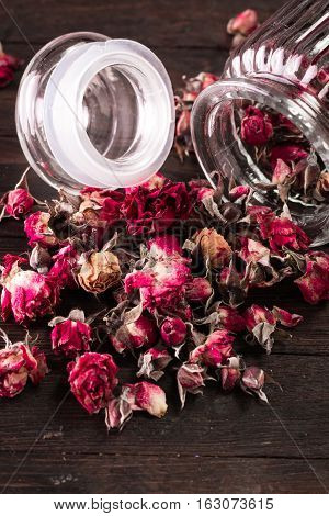Rose Petals And Dried Flowers In Jar On Old Wooden Table. Healthy Concept
