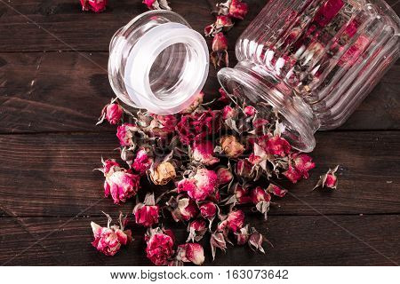 Rose Petals And Dried Flowers In Jar On Old Wooden Table. Healthy Concept