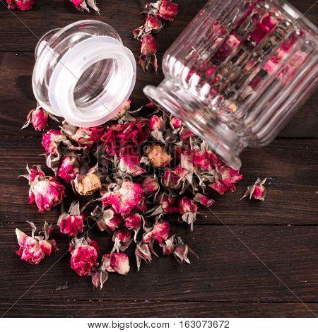 Rose Petals And Dried Flowers In Jar On Old Wooden Table. Healthy Concept