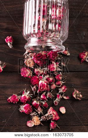 Rose Petals And Dried Flowers In Jar On Old Wooden Table. Healthy Concept