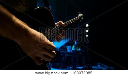The guitarist plays solo. Close-up. Dark background. Smoke