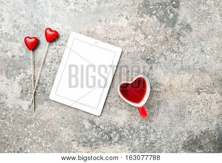 Tablet PC with red hearts decoartion and cup of tea. Valentines Day concept with space for your text and image
