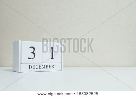 Closeup white wooden calendar with black 31 december word on blurred white wood desk and cream color wallpaper in room textured background with copy space selective focus at the calendar
