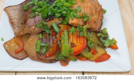 Grilled trout on white square plate with vegetables. View from above