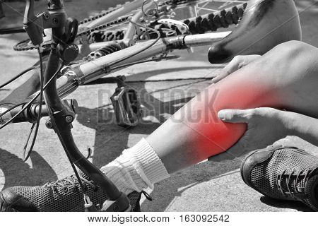 Man touch his leg and red point of pain from accident with bicycle black and white tone