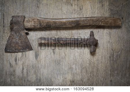 old iron ax and old iron hammer on the wooden tavle