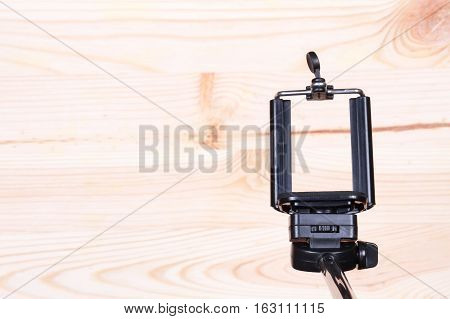 Monopod and phone on wood desk. Gadgetry on board.
