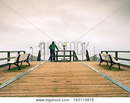 Man On Wooden Mole In Harbor Within Autumn Misty Day. Tourist At Handrail.