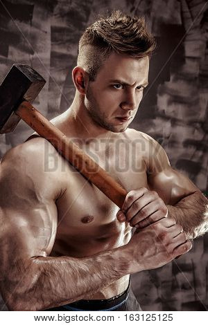 athlete and hammer - a very beautiful young guy with a nice muscle fitness and bodybuilder coach hold in strong arms and big metal hammer
