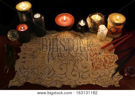Black magic ritual or spell with demon manuscript and evil candles. Halloween concept. Occult objects on table. There is no foreign text in the image, all symbols are imaginary and fantasy ones