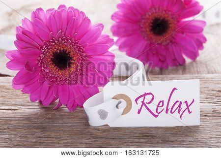Label With English Text Relax. Pink Spring Gerbera Blossom. Vintage, Rutic Or Aged Wooden Background. Card For Spring Greetings.