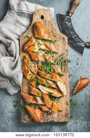 Turkish oriental pizza pide with cheese and spinach chopped in slices on wooden board over grey stone background, top view, vertical composition