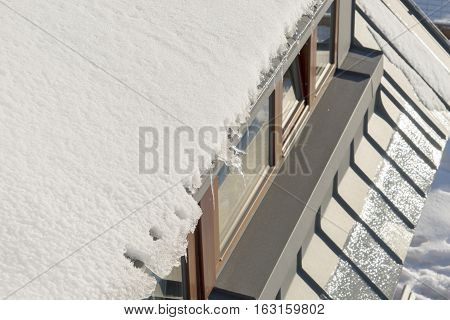 Snow hanging on the roof above the windows