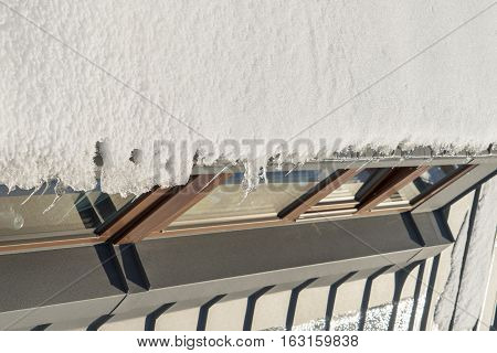 Snow hanging on the roof above the windows