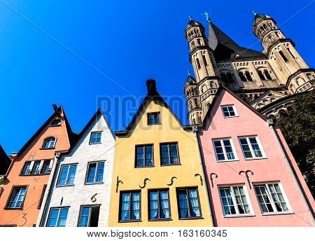A row of colorful houses on the banks of the Rhine in front of the St. Martin Church in Cologne, Rhineland, Germany