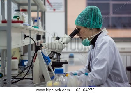 Beautiful Female Medical Or Scientific Researcher Or Woman Doctor Looking Through A Microscope In A