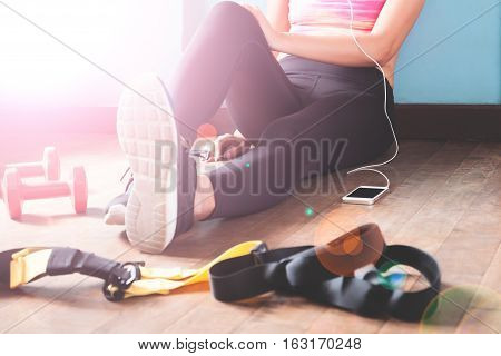 Female fitness resting and relaxing after workout. Woman sitting down on wood floor. Sport Fitness Healthy lifestyle concept