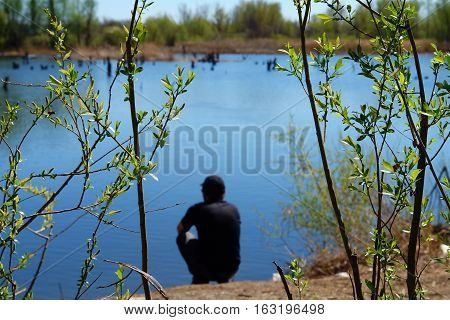 Blurred Man silhouette sitting on the river bank