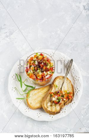 Salad Salsa of colorful vegetables in a glass batch with toasted grilled on a light background. Top view