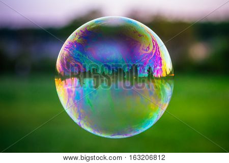 Reflection of the colorful sunset sky in the soap bubble